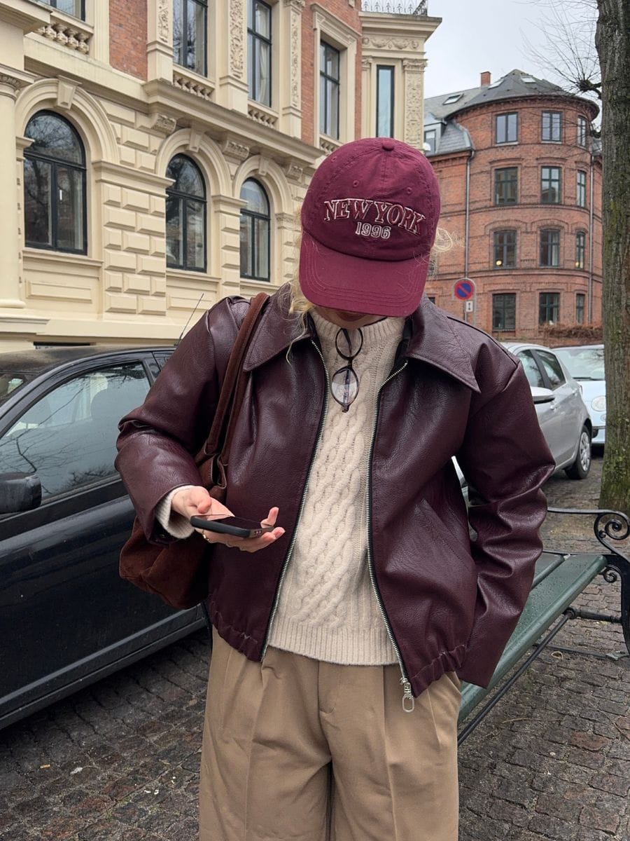 Bordowa kurtka oversize Emmy na spacerze, stylizacja z czapką i swetrem warkoczowym